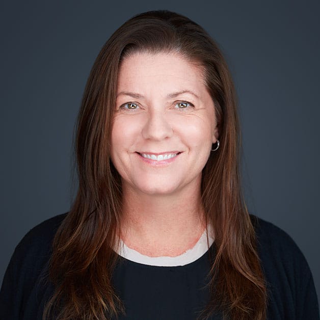 A woman with long brown hair smiling for the camera.